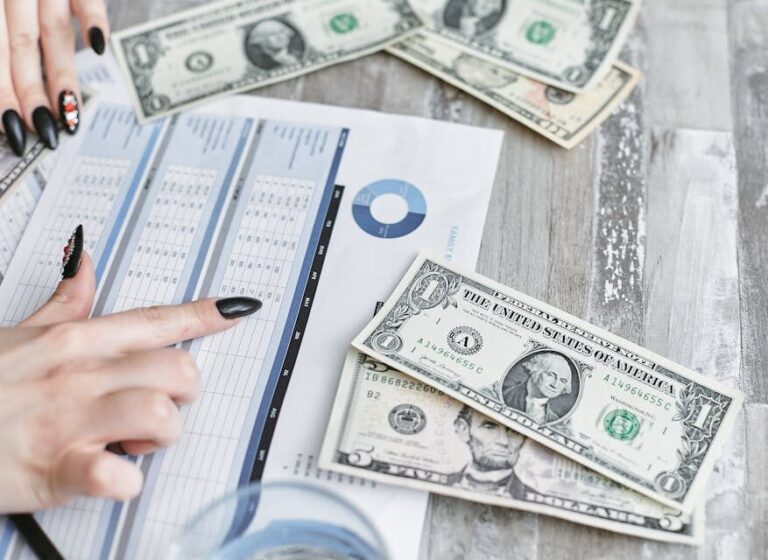 Close-up of hands analyzing financial document with US dollar bills on table.